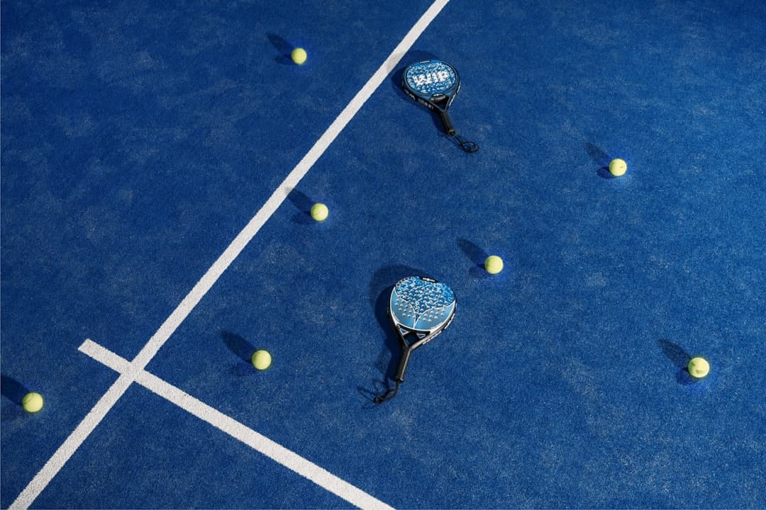 Zwei Padelschläger und Bälle auf blauem Padelplatz